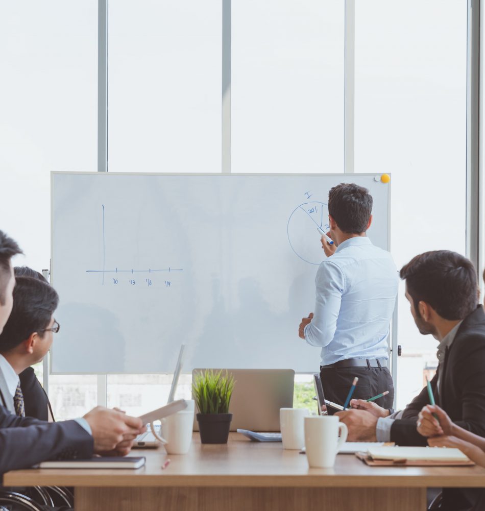 businessman-leader-writing-whiteboard-present-business-marketing-graph-while-meeting-with-colleagues-office-business-team-meeting-presentation-conference-planning-business-concept (1)